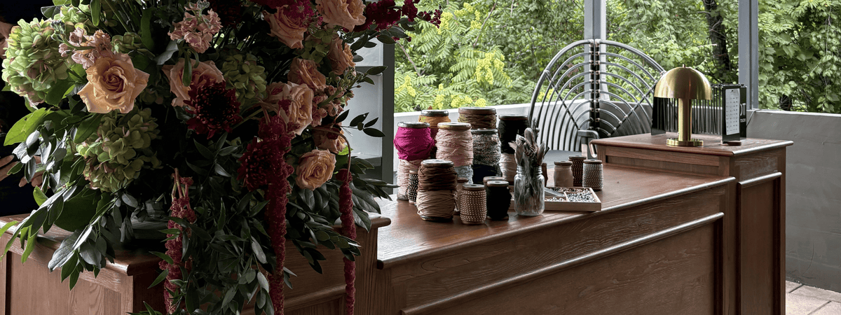 Hat accessories on the table beside a flower arrangement at a custom hat bar event.