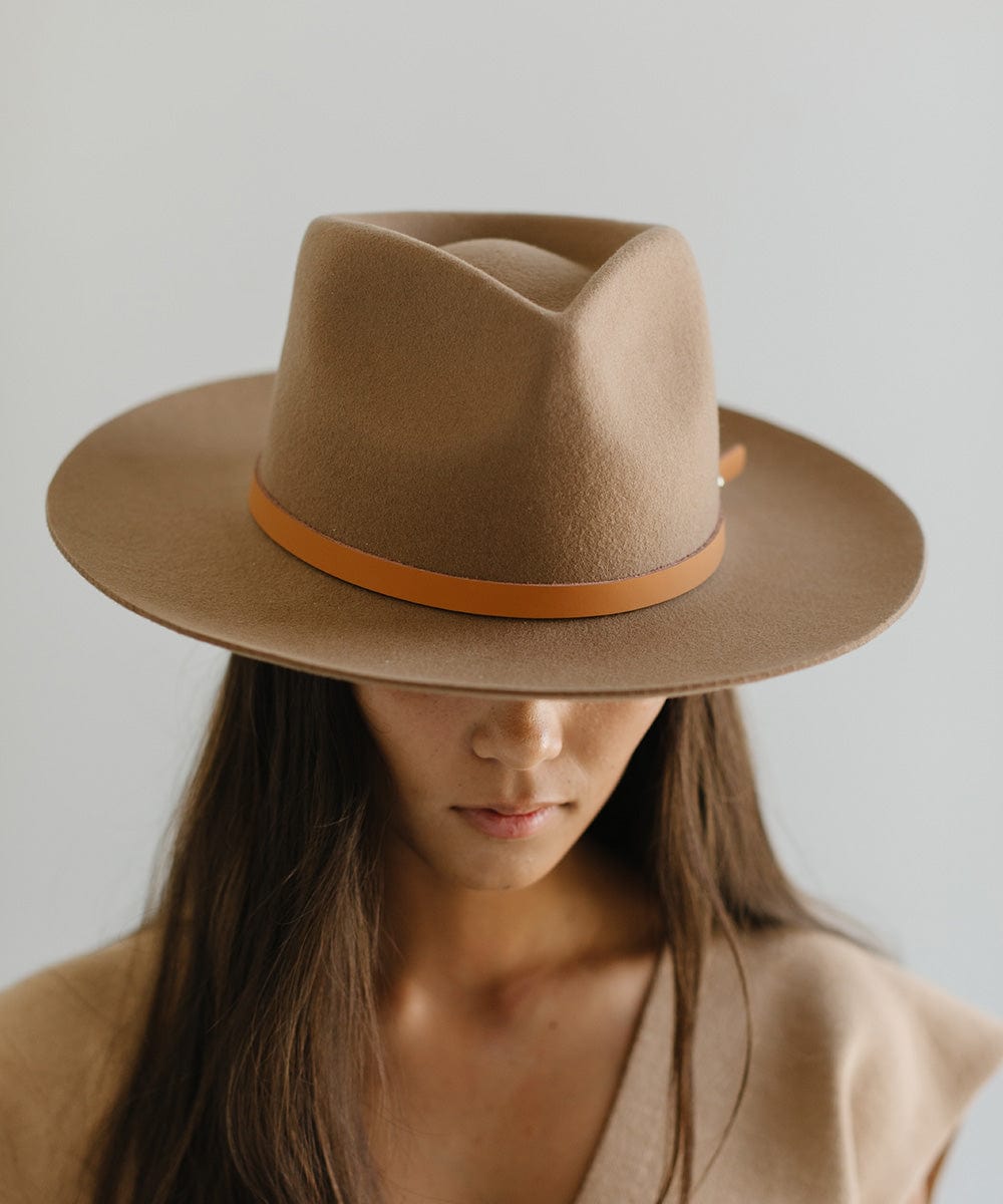 Woman wearing a beige felt hat with a thin cognac leather hat band around the base against a plain background #color_cognac