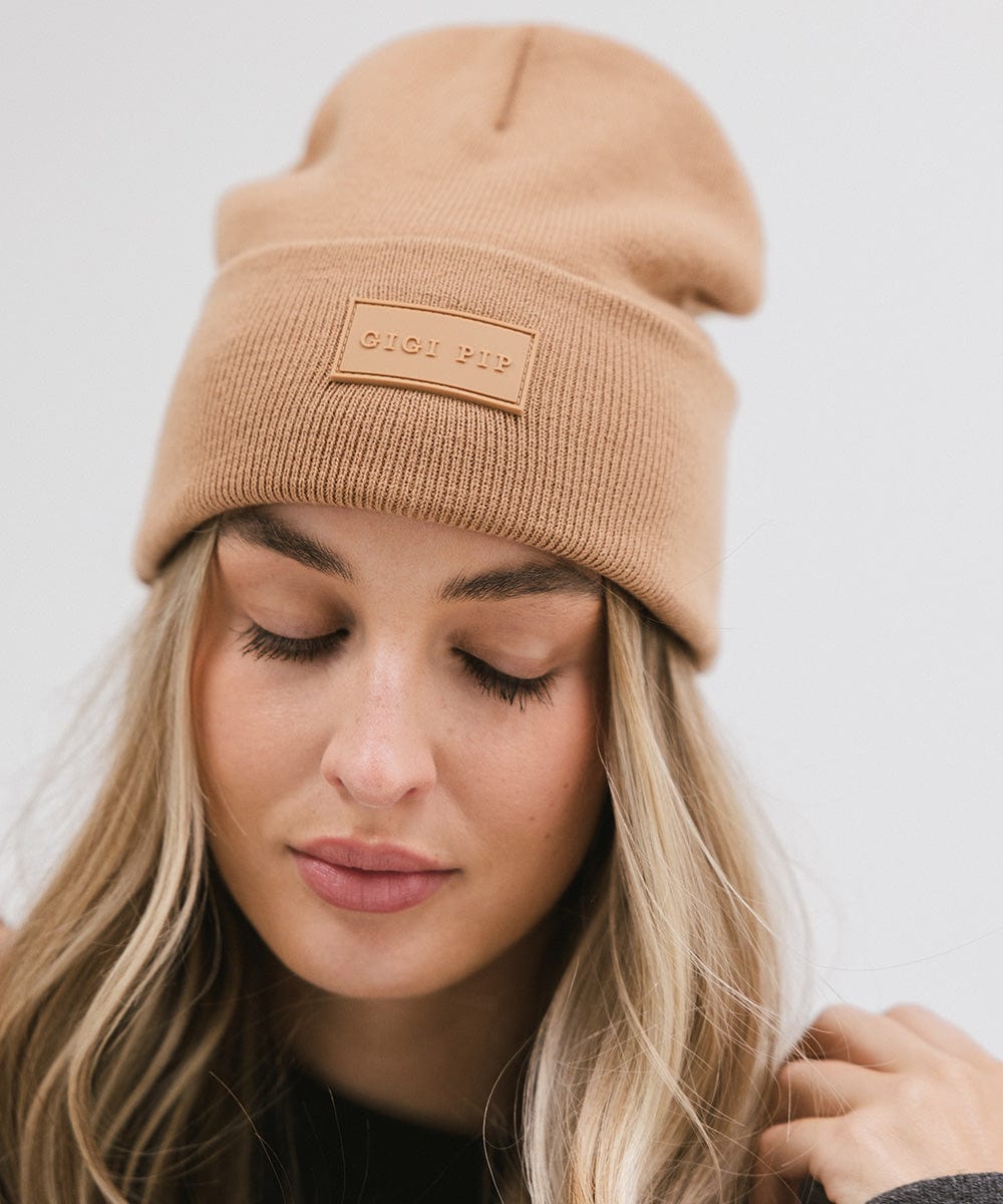 Close up image of a woman wearing a latte colored knit beanie against a plain background #color_latte