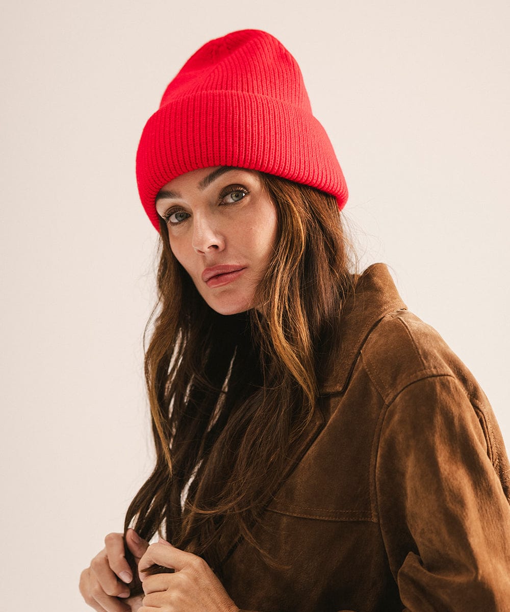 Woman wearing a red beanie and brown jacket against a plain background #color_red