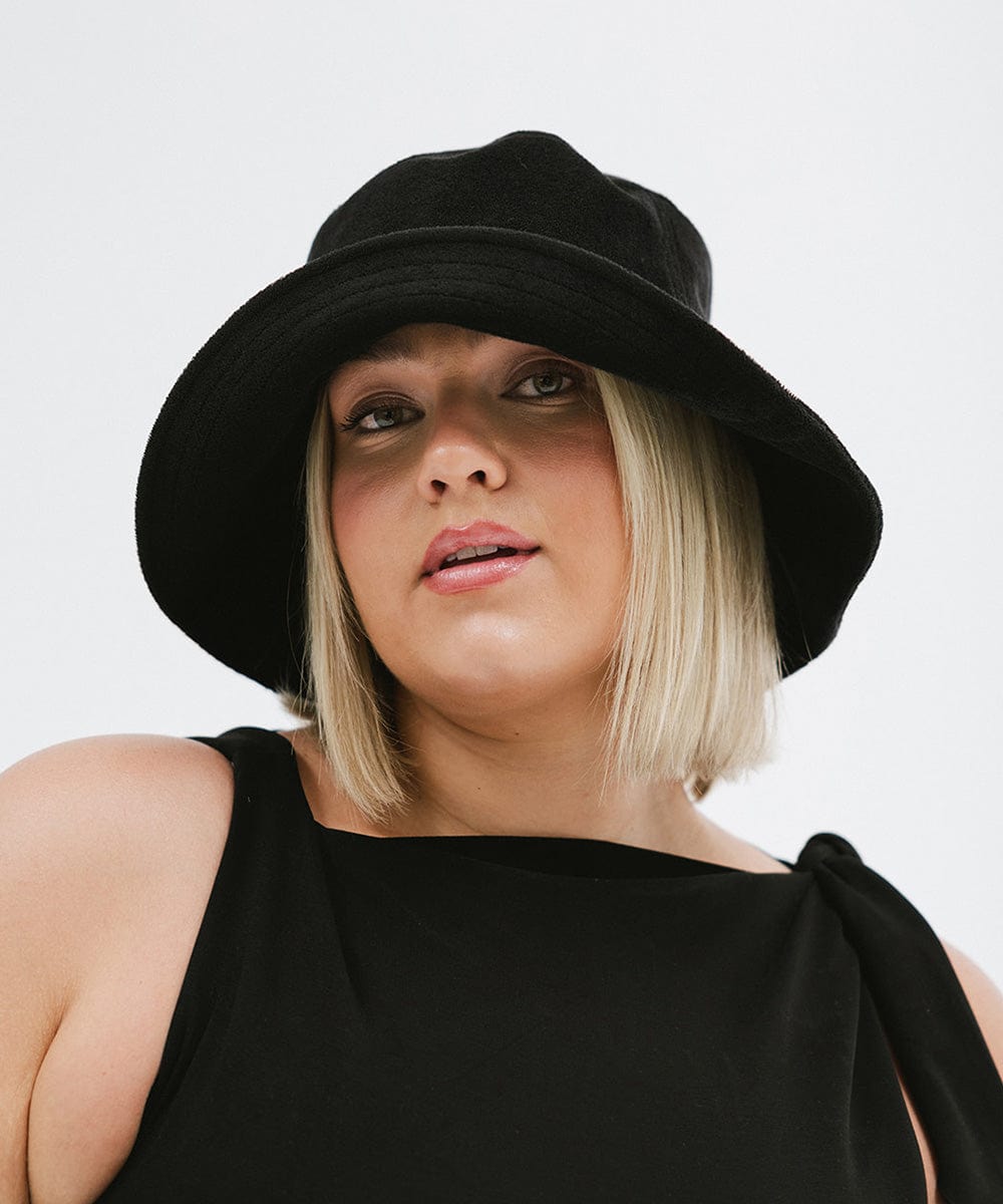 Woman wearing a black bucket hat and a black top against a plain background #color_black