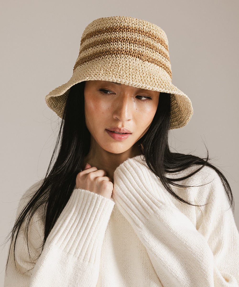 Woman wearing a beige crochet packable bucket hat and a white sweatshirt against a plain background #color_natural stripe