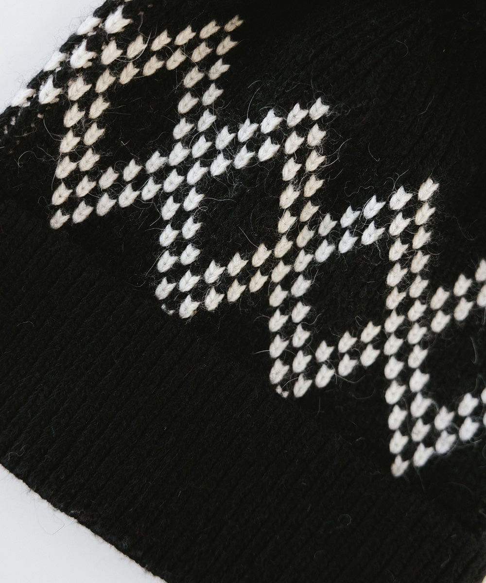 Close up image of a black knit beanie on a white background #color_black