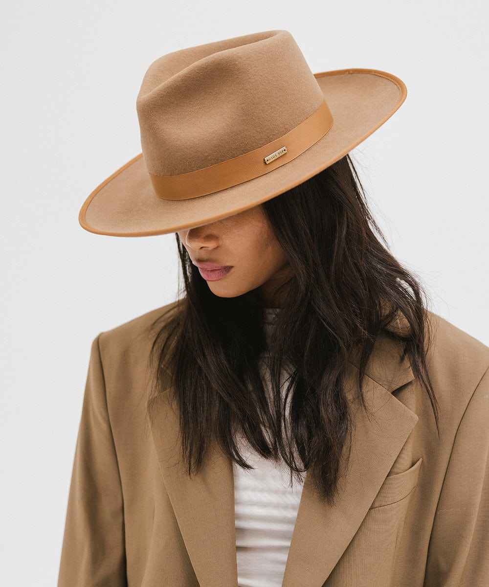 Woman wearing a brown hat with a band and a brown blazer against a plain background #color_brown