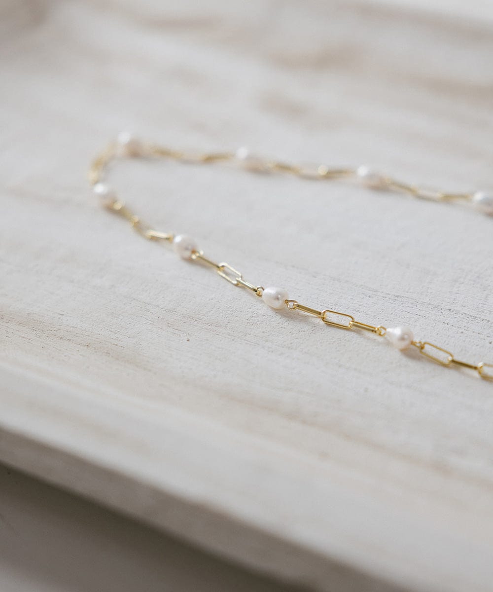 A gold pearl paperclip chain band on a plain background #color_gold