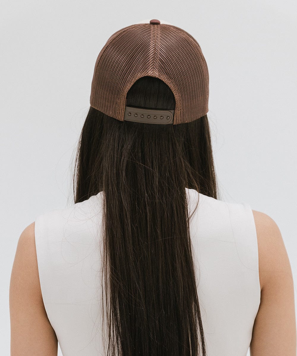 Woman with long hair wearing a cream and chocolate brown cap and a white top against a plain background #color_cream - chocolate brown
