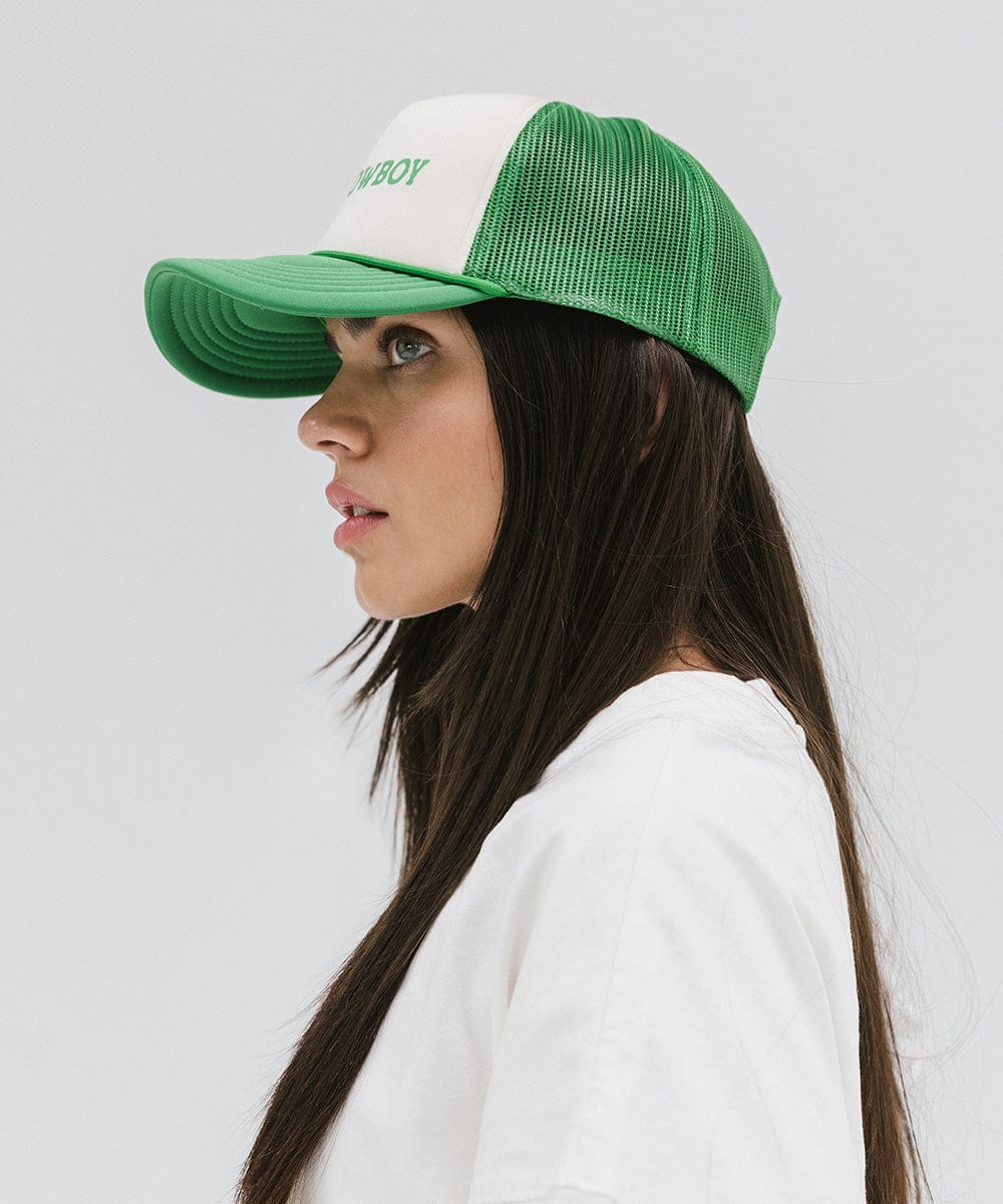 Woman wearing a cream and vintage green cap and a white t-shirt, facing sideways against a plain background #color_cream - vintage green