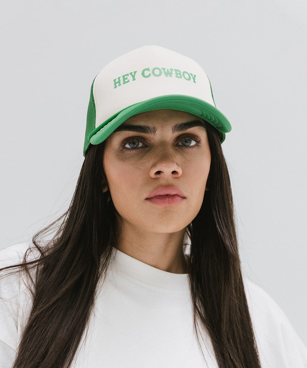 Woman wearing a cream and vintage green cap with 'Hey Cowboy' text and a white t-shirt against a plain background #color_cream - vintage green