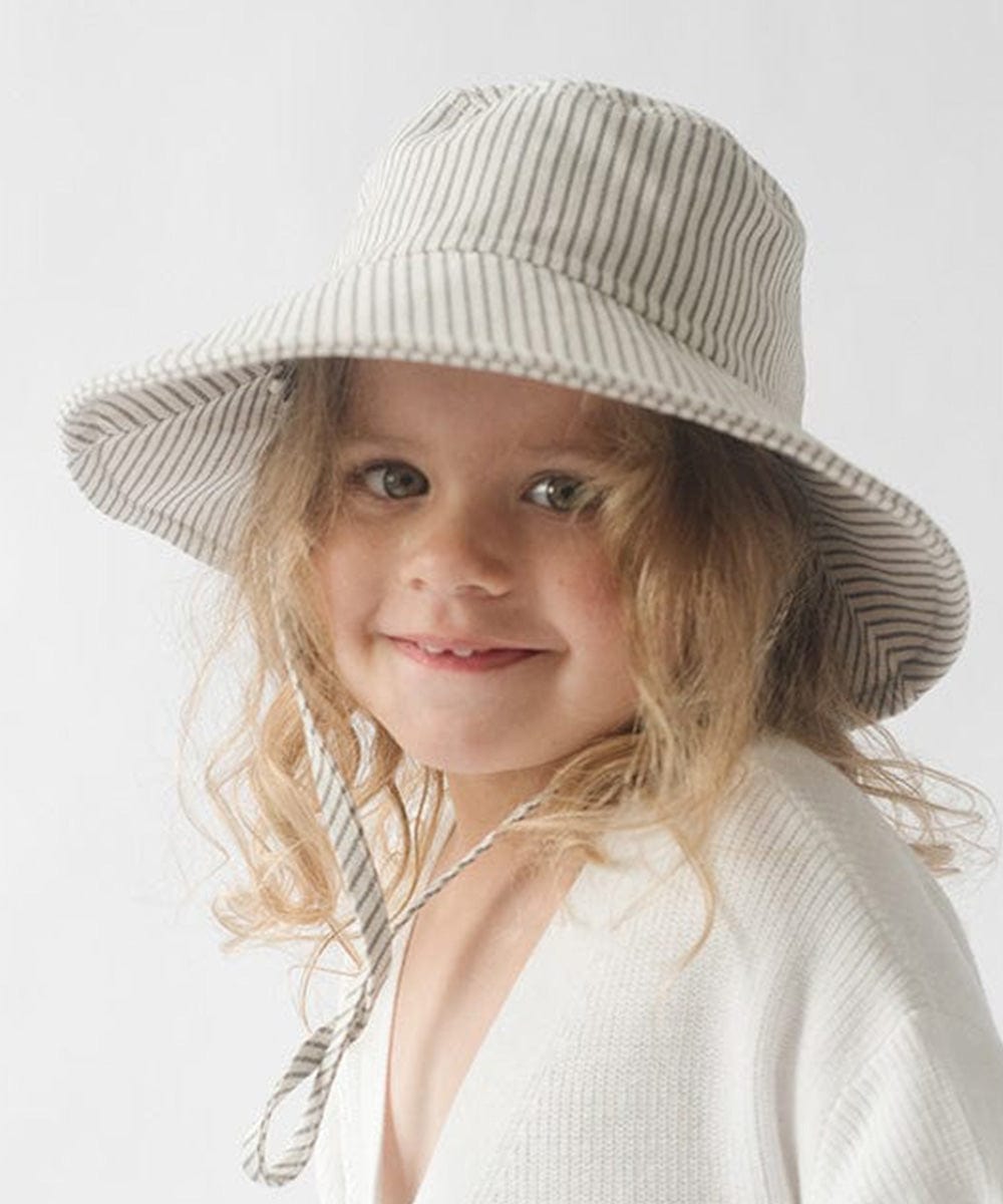 Young girl wearing a grey striped bucket hat and a white shirt against a plain background #color_grey