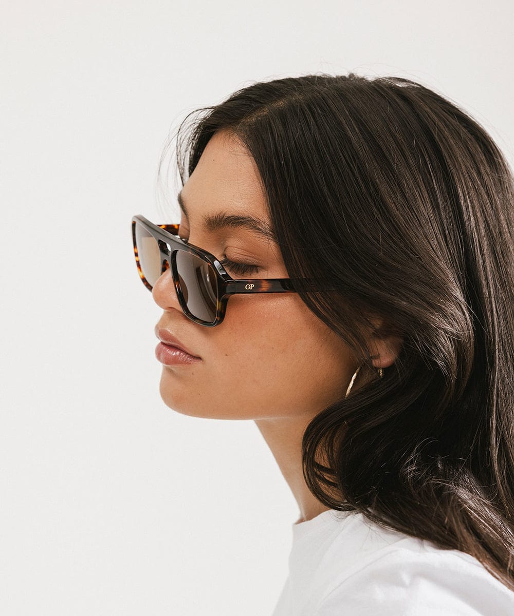 Woman wearing sunglasses with a plain background #color_tortoise