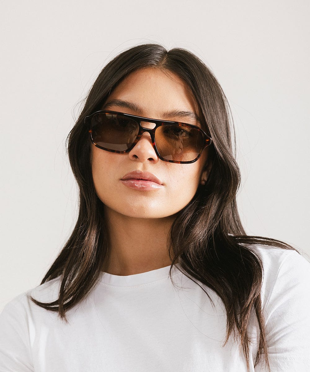 Woman wearing sunglasses with a plain background #color_tortoise