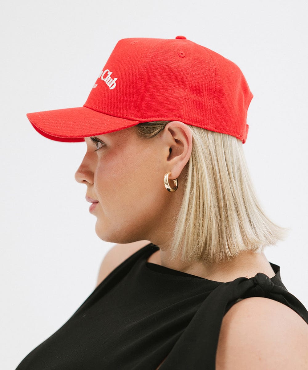 Woman wearing a red cap and a black top, facing sideways against a plain background #color_red