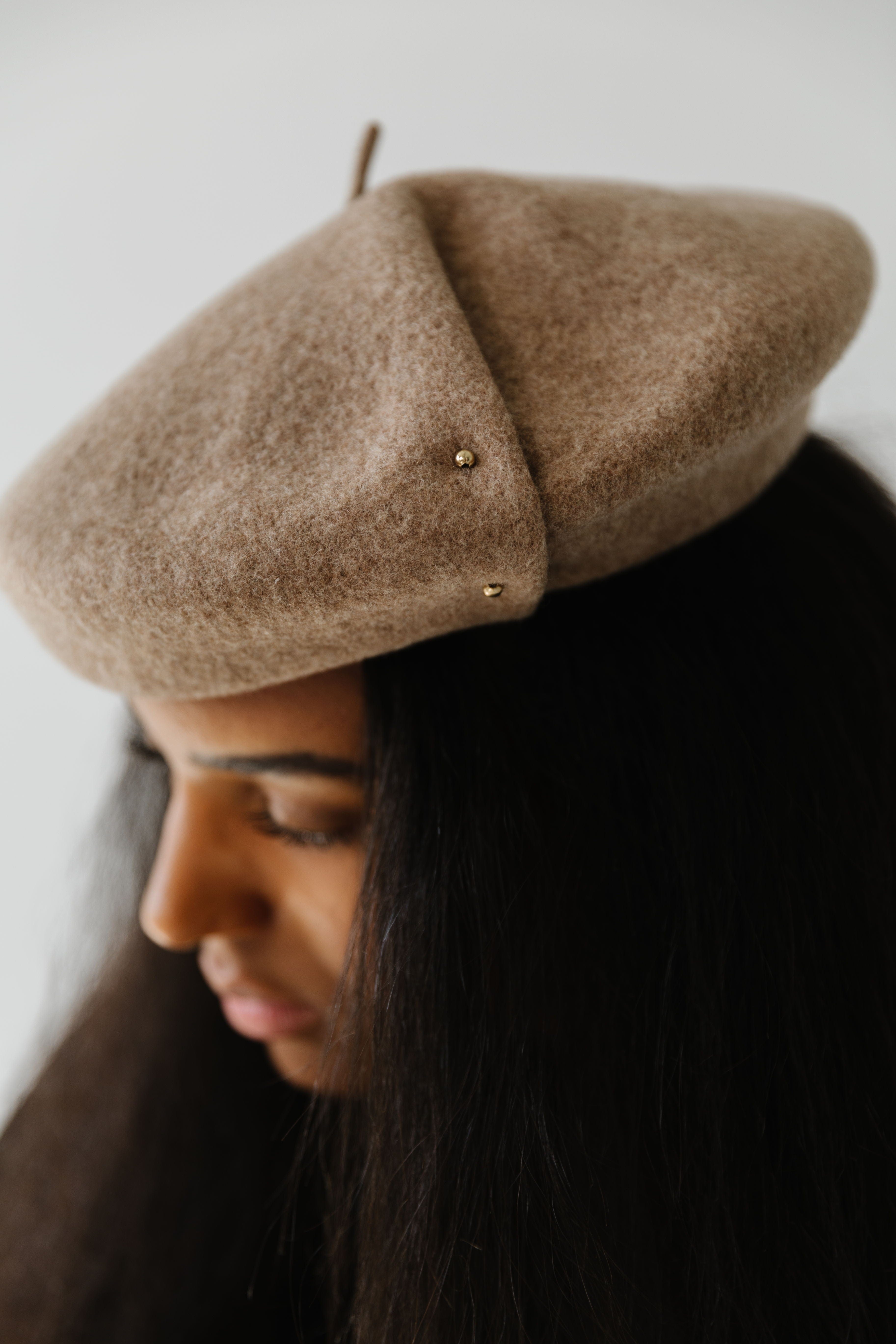 Woman wearing a camel colored beret facing sideways against a plain background #color_camel