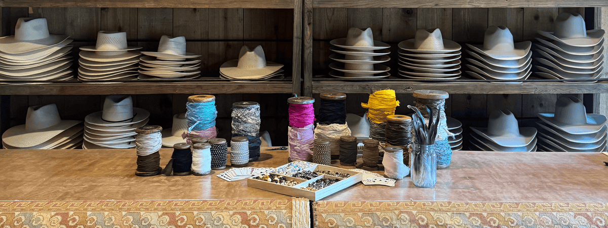 Hat accessories on a table and several hats displayed behind the table at a custom hat bar event.