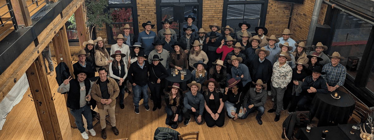 People in a group photo wearing hats at a custom hat bar event.