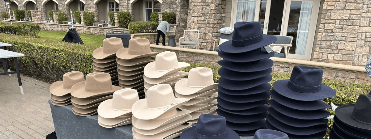 Several felt hats on a table outside at a custom hat bar event.