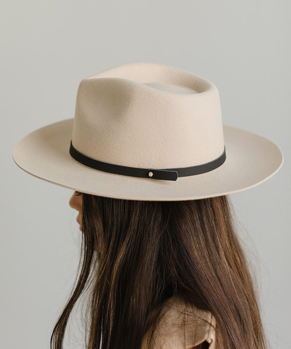 Woman wearing a beige felt hat with a thin black leather hat band around the base, facing sideways against a plain background #color_black