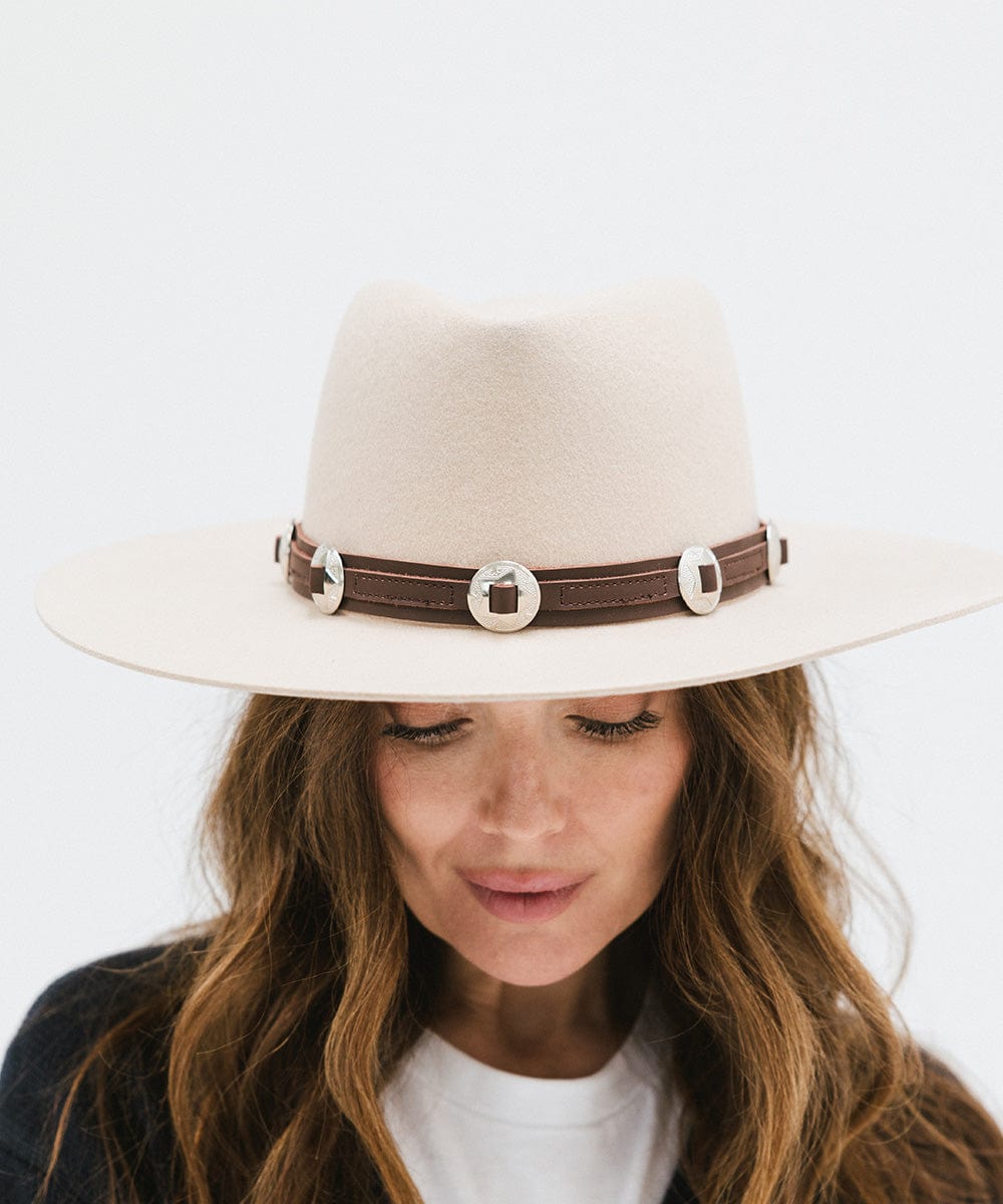 Woman wearing a white hat with a chocolate colored western style  genuine leather hat band against a plain background #color_chocolate