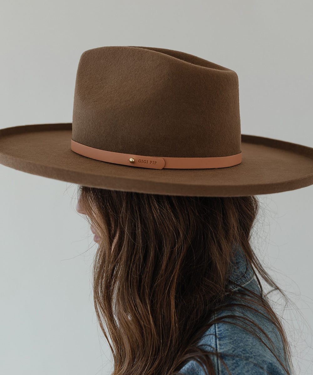 Woman wearing a brown hat with a sunset colored genuine leather thin hat band against a plain background #color_sunset