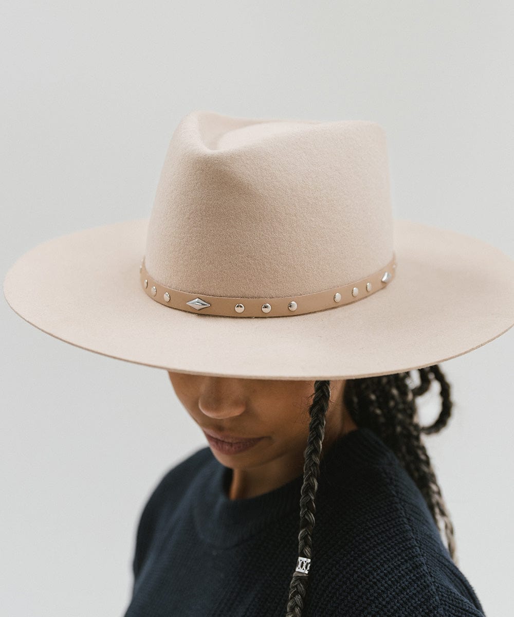 Woman wearing a cream hat with a tan studded leather hat band against a plain background #color_tan