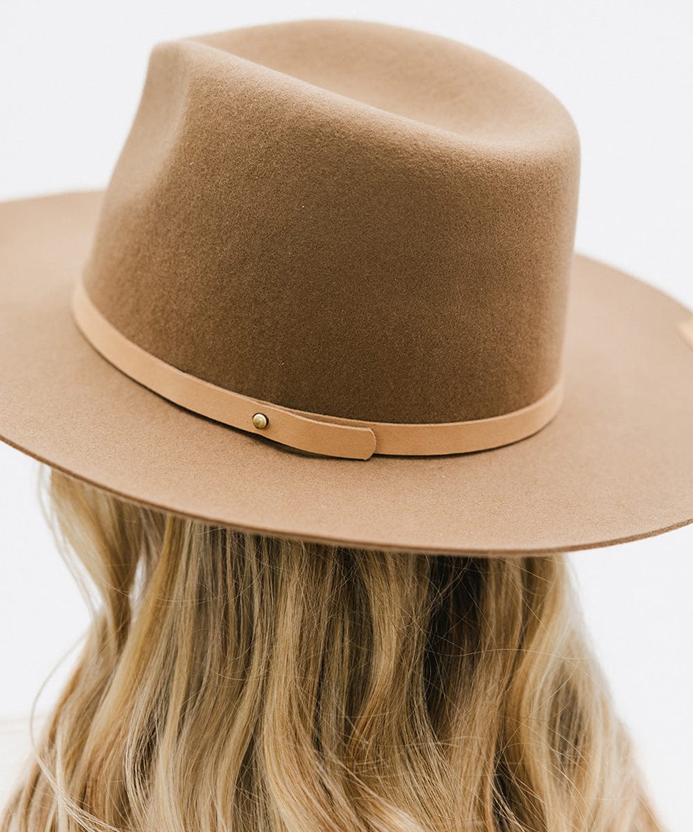 Woman wearing a beige felt hat with a thin blush colored leather hat band around the base against a plain background  #color_blush