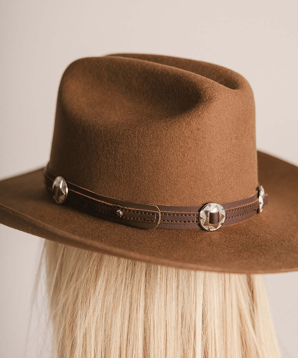 Brown cowboy hat with decorative band on a neutral background #color_chocolate