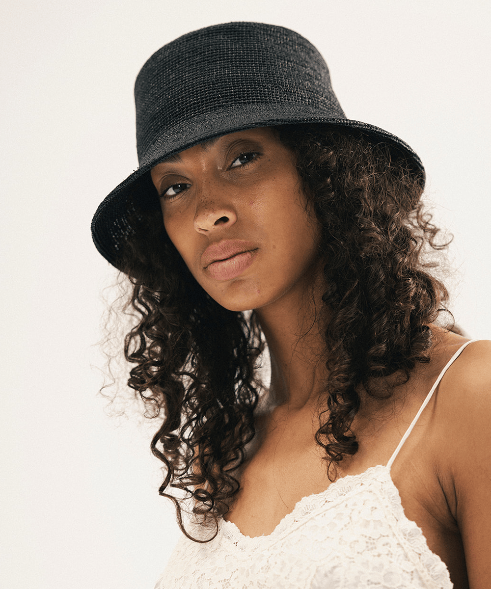 Woman wearing a black bucket hat against a white background #color_black
