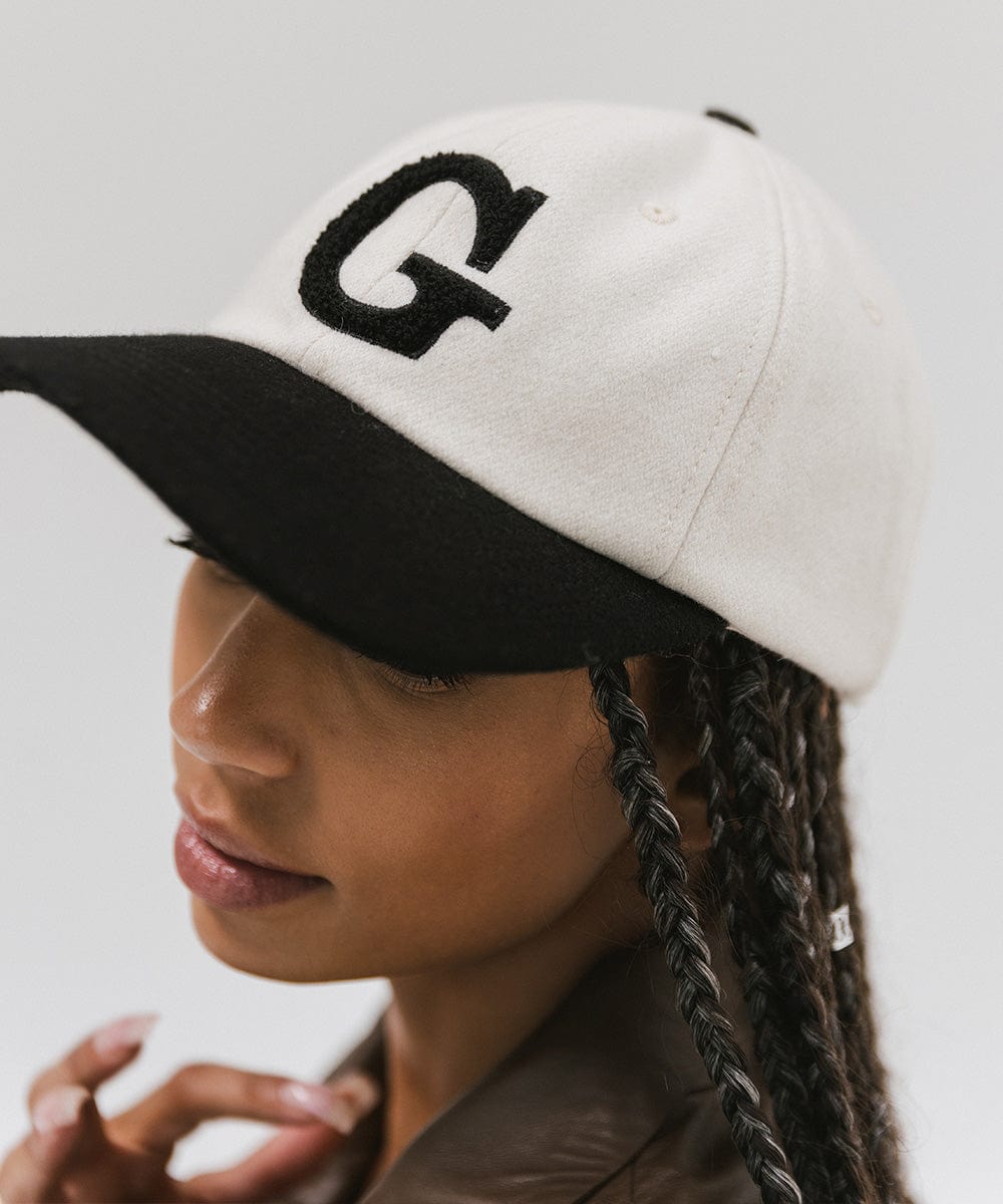Woman wearing a cream and black baseball cap with the letter 'G' against a plain background  #color_cream-black