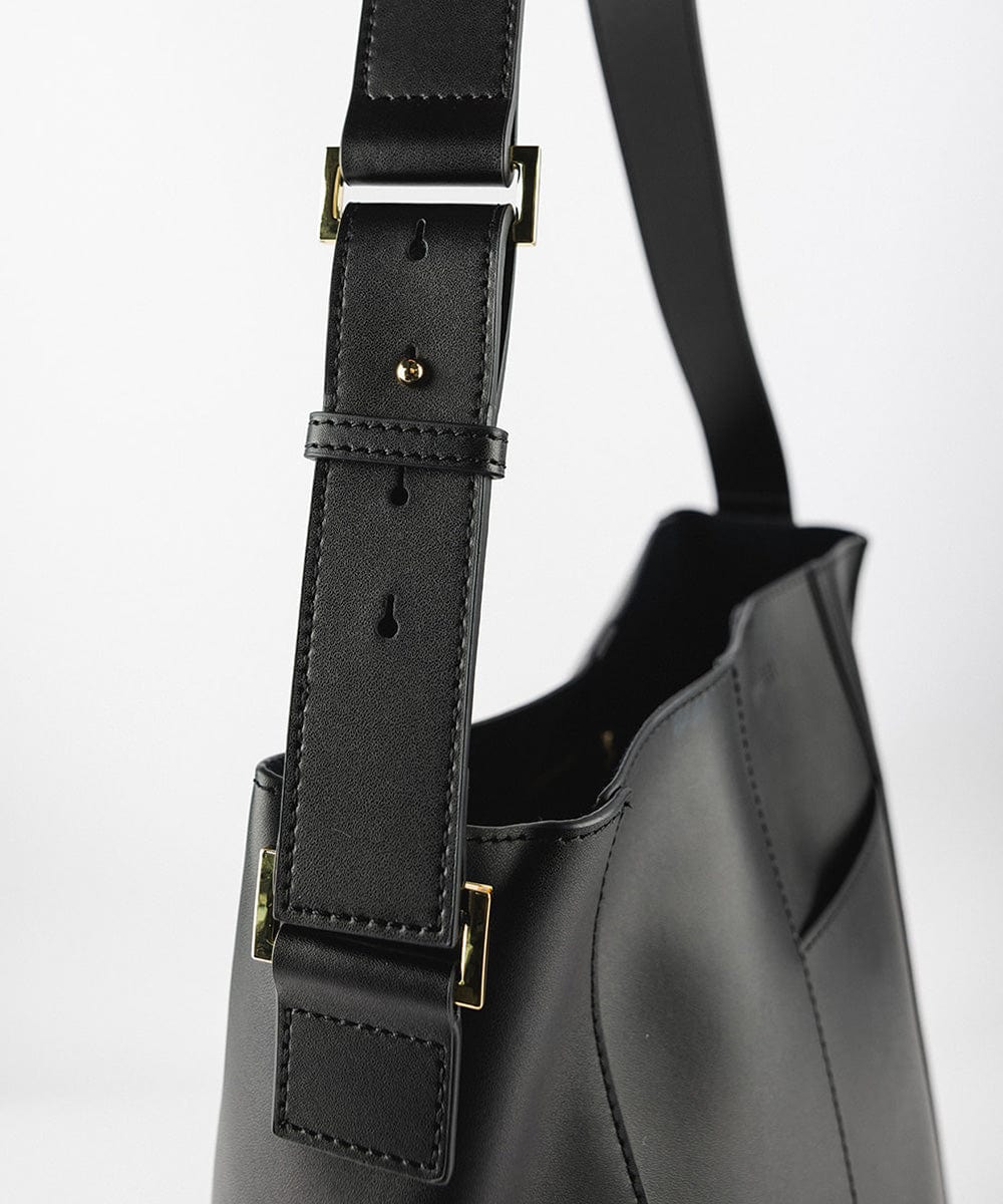 Close up image of the side of a black Dia Everyday Leather Tote Bag against a plain background  #color_black