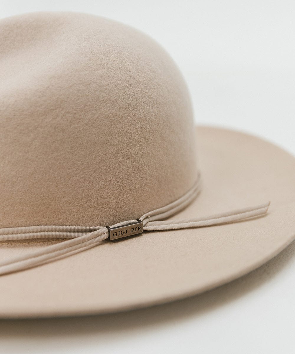 Close up image of a cream fedora hat with a hat band on a plain background #color_cream