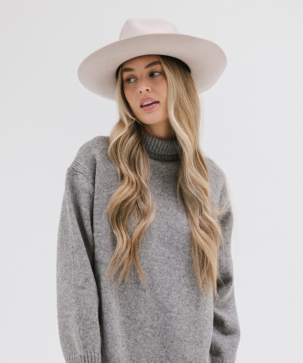 Woman with long blonde hair wearing an ivory colored Rowan Wide Brim Fedora Hat and a grey sweatshirt against a plain background #color_ivory