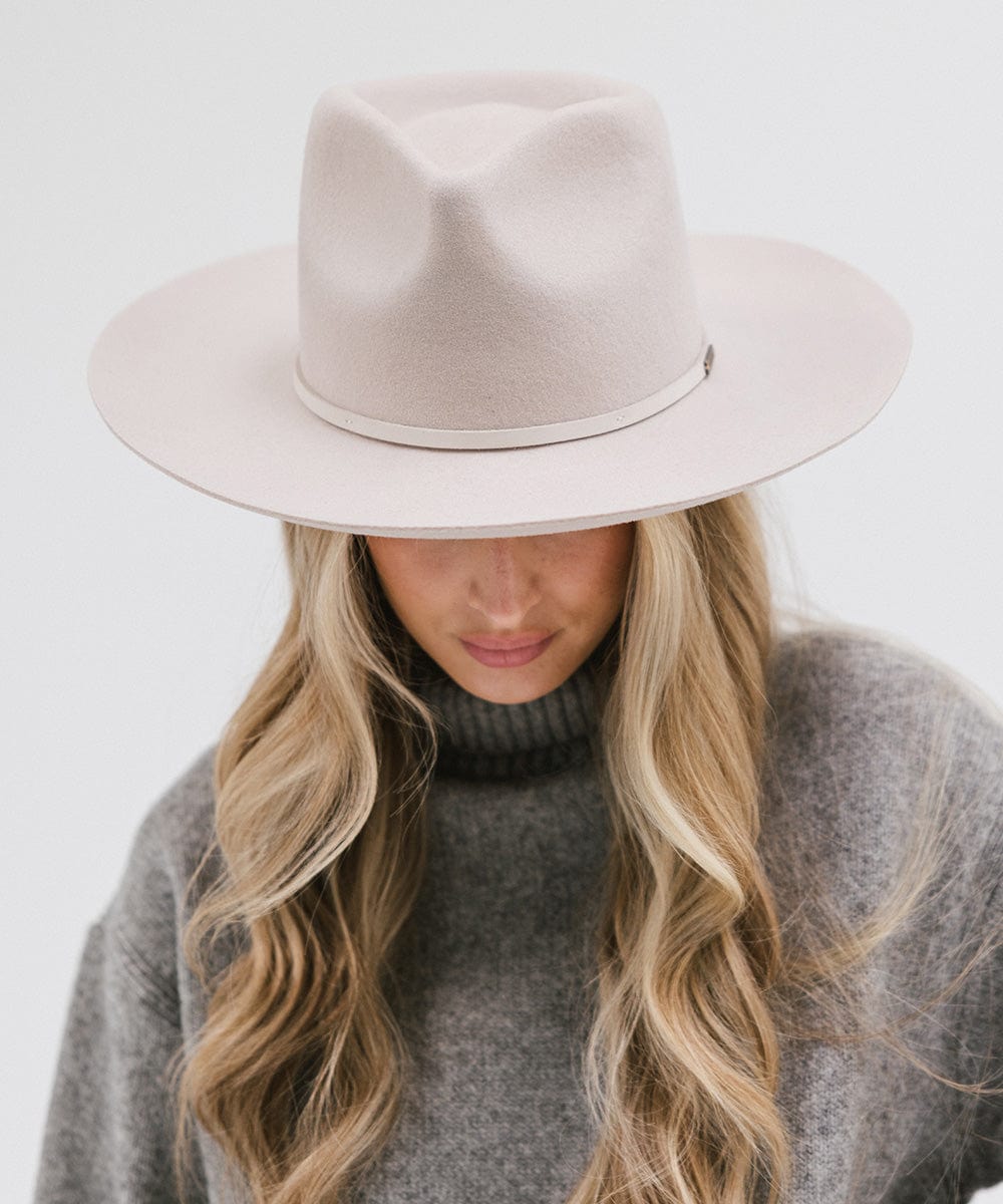 Woman wearing an ivory colored Rowan Wide Brim Fedora Hat with a hat band and a grey sweatshirt against a plain background #color_ivory