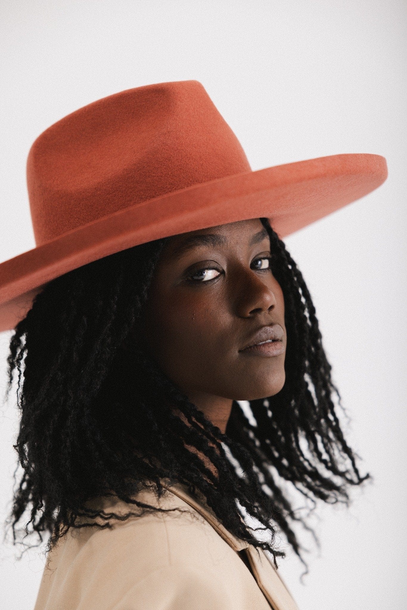 Woman wearing a clay colored pencil brim fedora hat with a wide brim  against a white background #color_clay