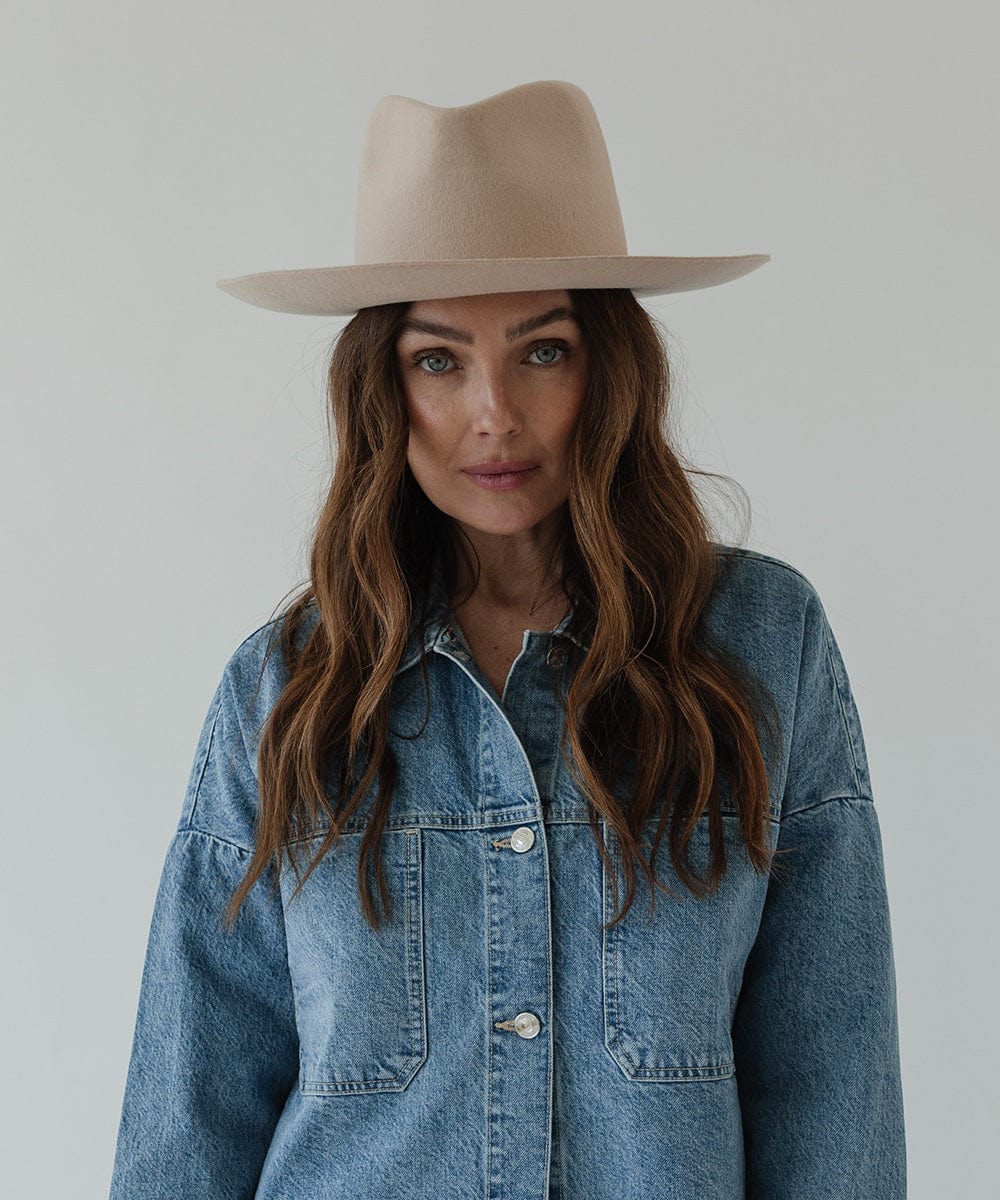 Woman wearing a cream fedora hat and a denim shirt against a plain background #color_cream