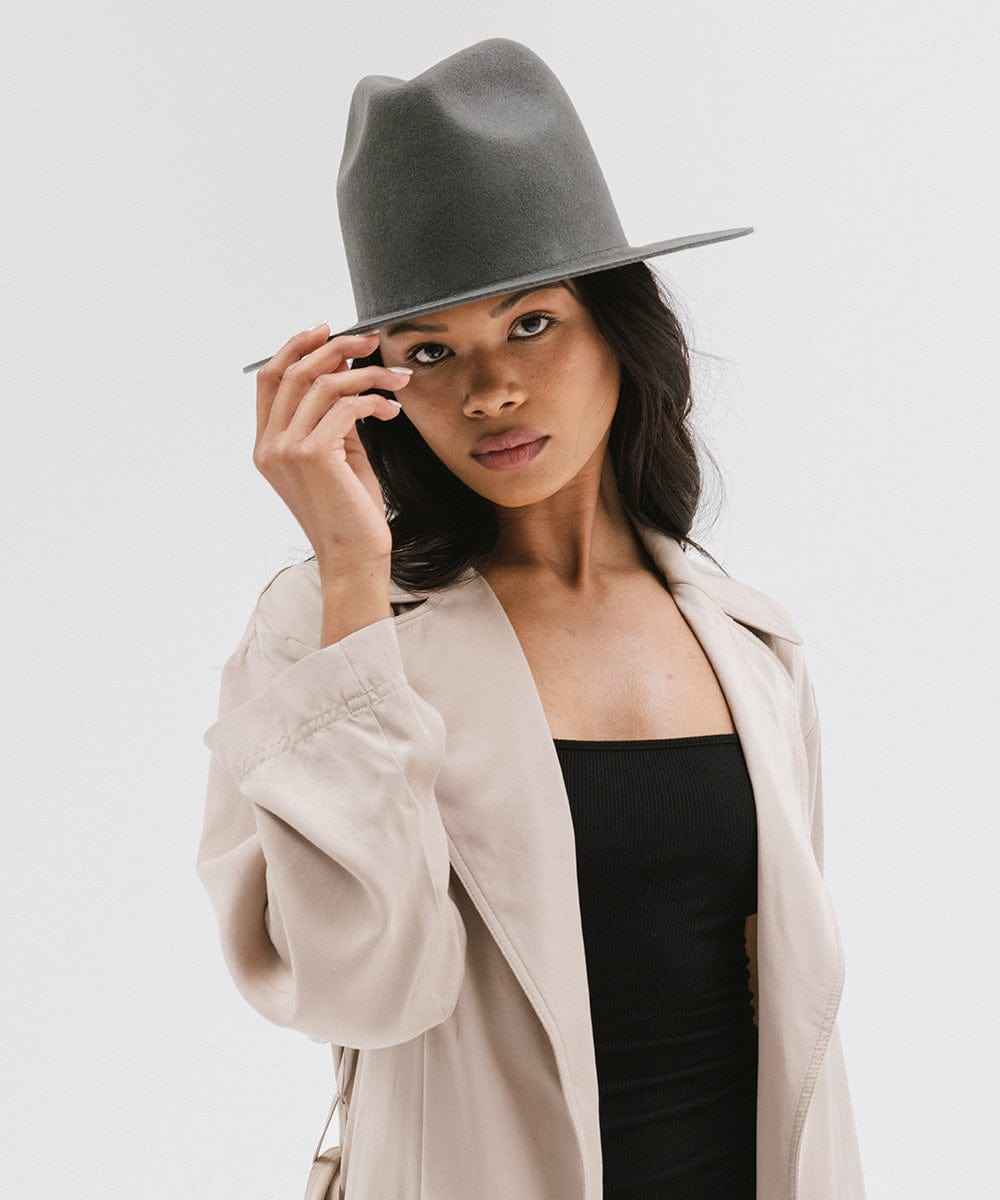 Woman wearing a grey fedora hat and beige jacket on a white background #color_dark grey