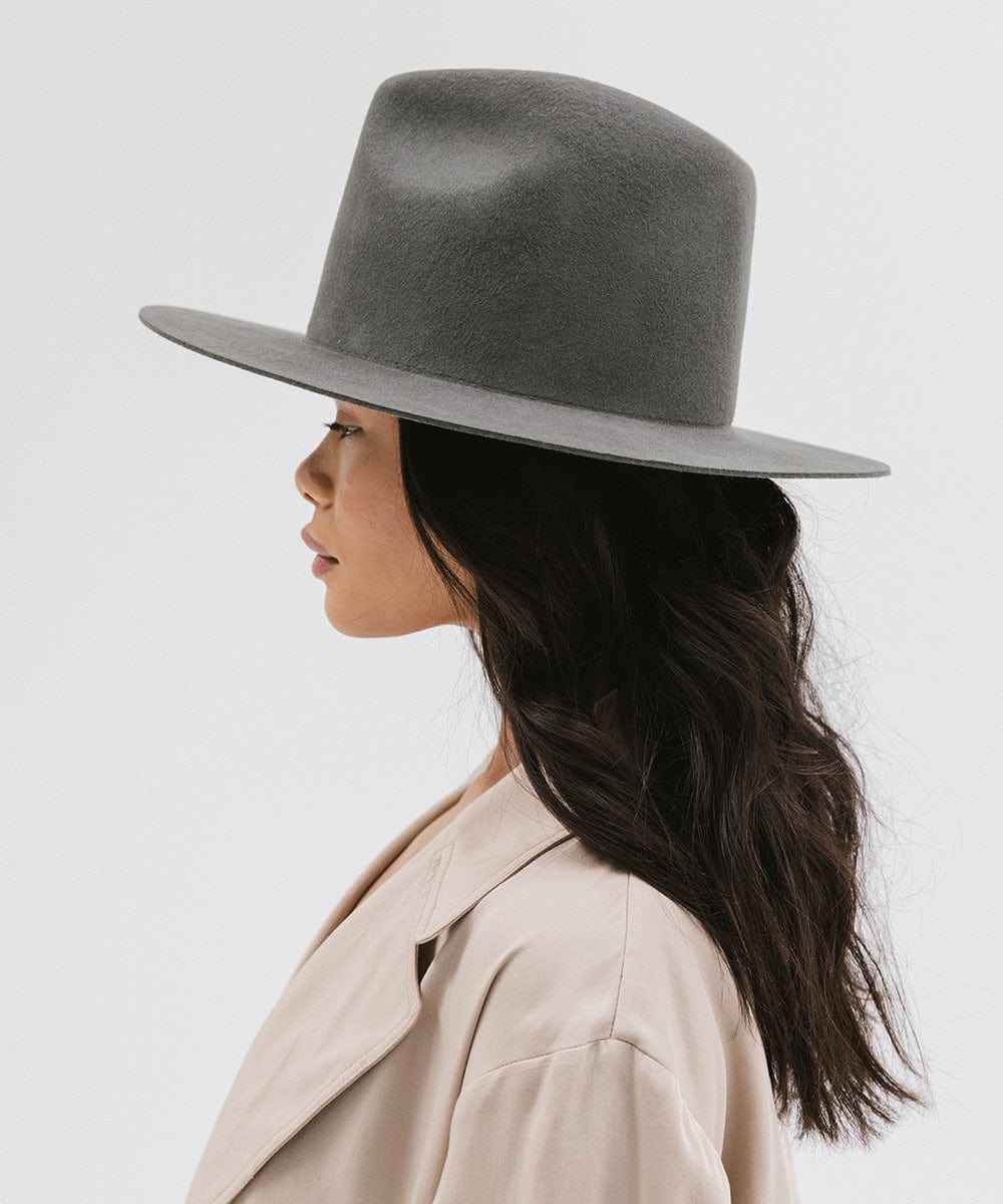 Woman wearing a grey fedora hat and beige trench coat on a white background #color_dark grey