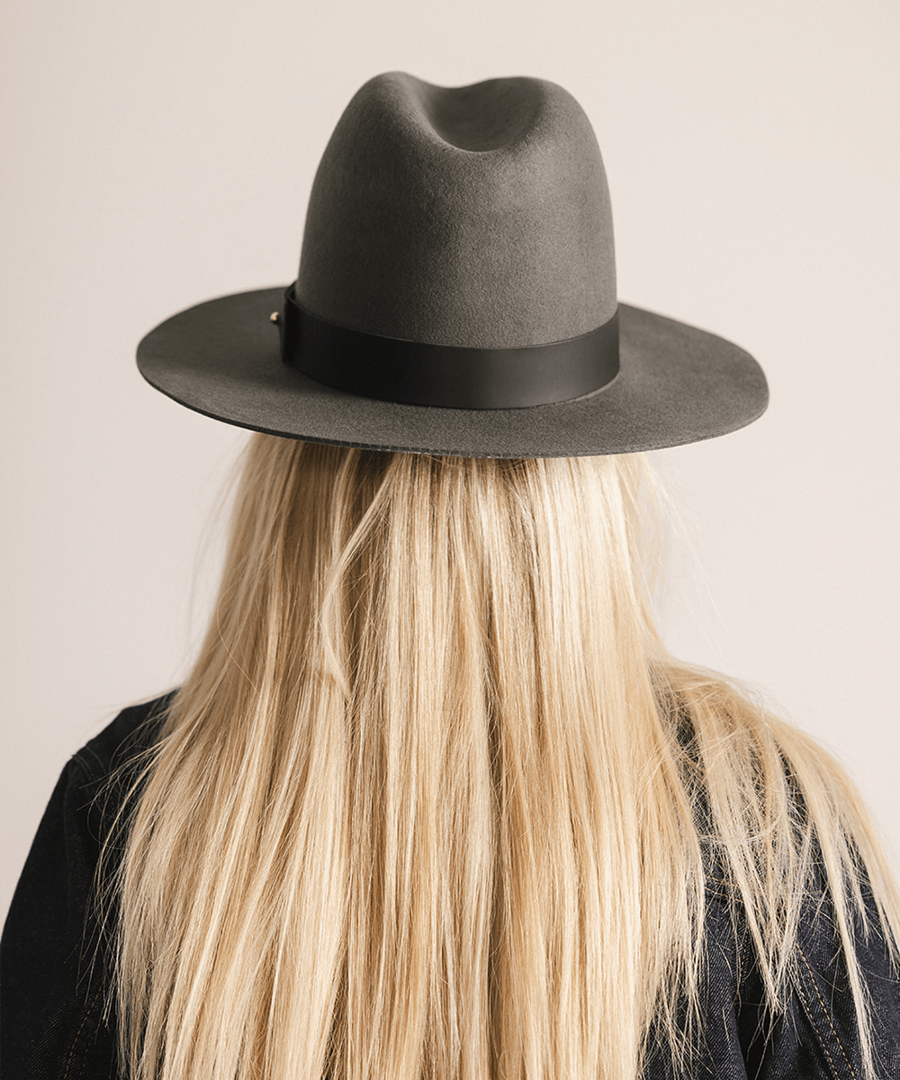 Woman wearing a grey fedora hat on a white background #color_dark grey