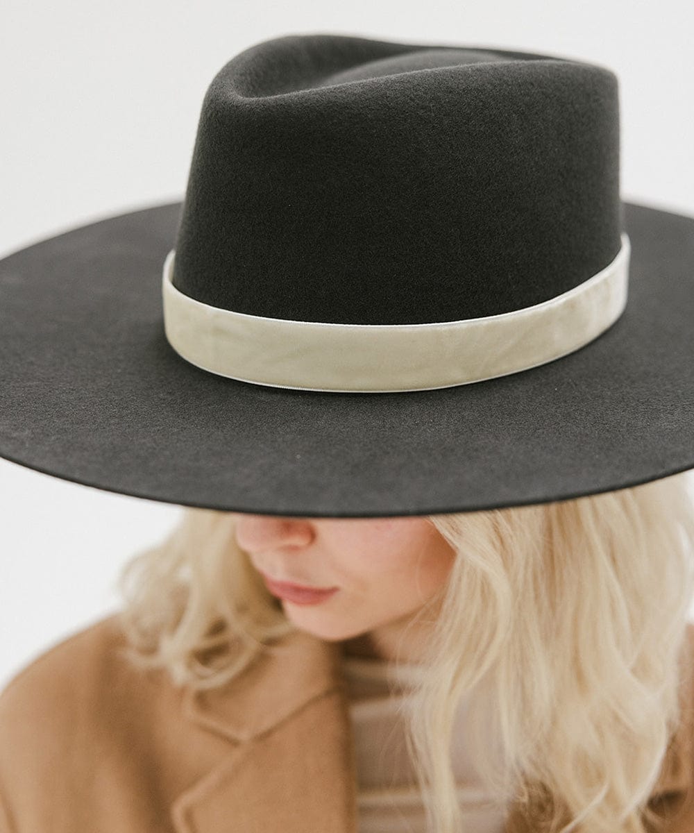 Woman wearing a dark grey wide brim felt hat with a triangle crown and a hat band against a white background #color_dark grey