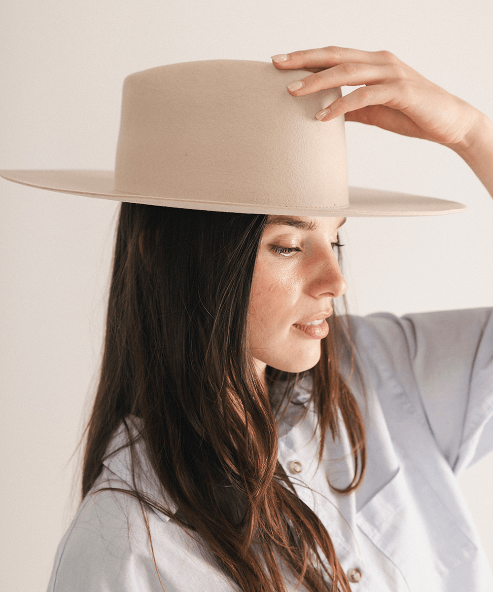 Woman wearing a wide brim felt hat on a white background #color_cream