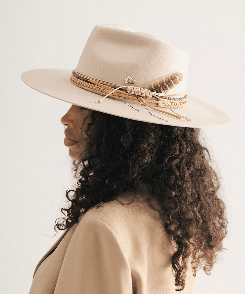 Woman wearing a beige cowboy hat with braided detail against a white background #color_tan