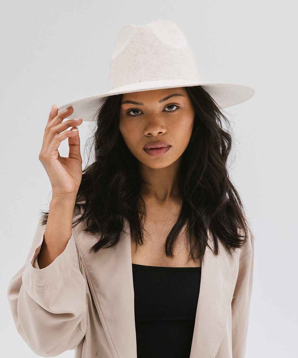 Woman wearing a mix ivory colored wide brim hat and a beige coat against a plain background #color_mix ivory