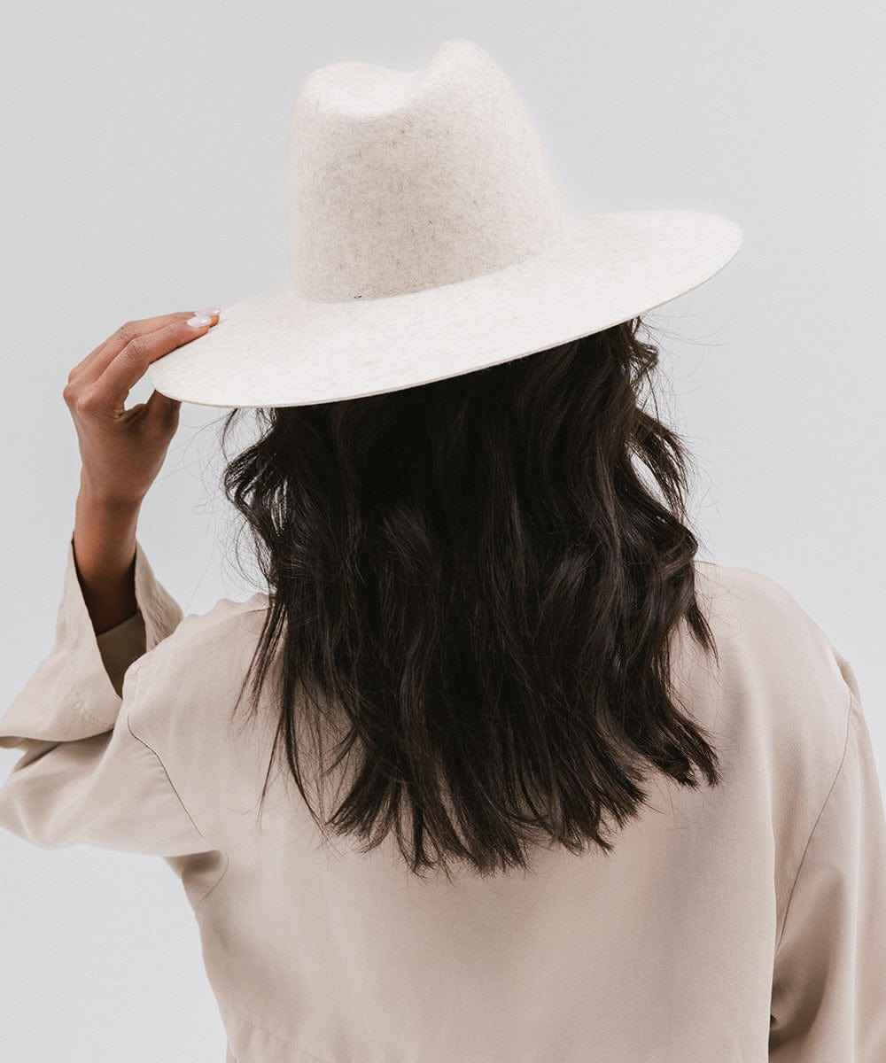 Person wearing a mix ivory colored wide brim hat and a beige coat against a plain background #color_mix ivory