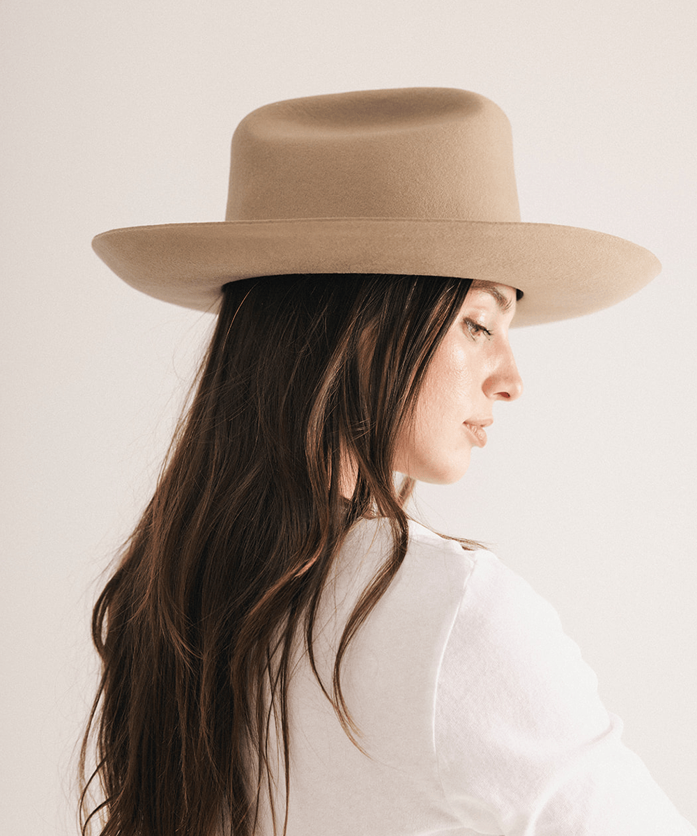 Woman wearing a western felt hat on a white background #color_tan