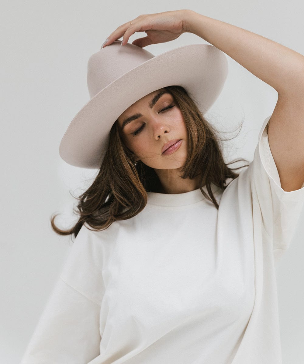 Woman wearing an ivory colored Western hat and a white t-shirt, posing against a plain background #color_ivory