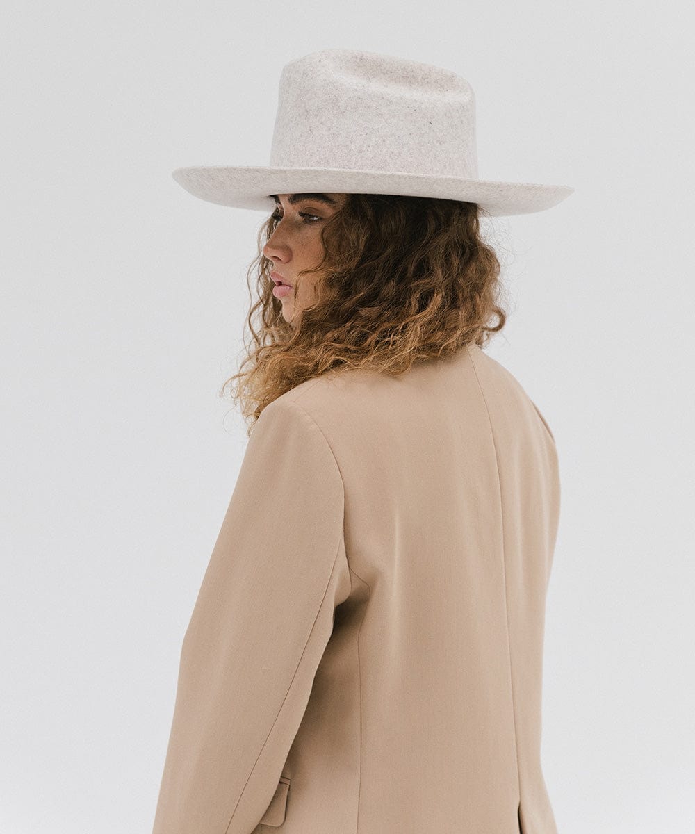Woman wearing a mix grey colored Western hat with a classic cattleman crown, and a beige coat, facing sideways against a plain background  #color_mix grey