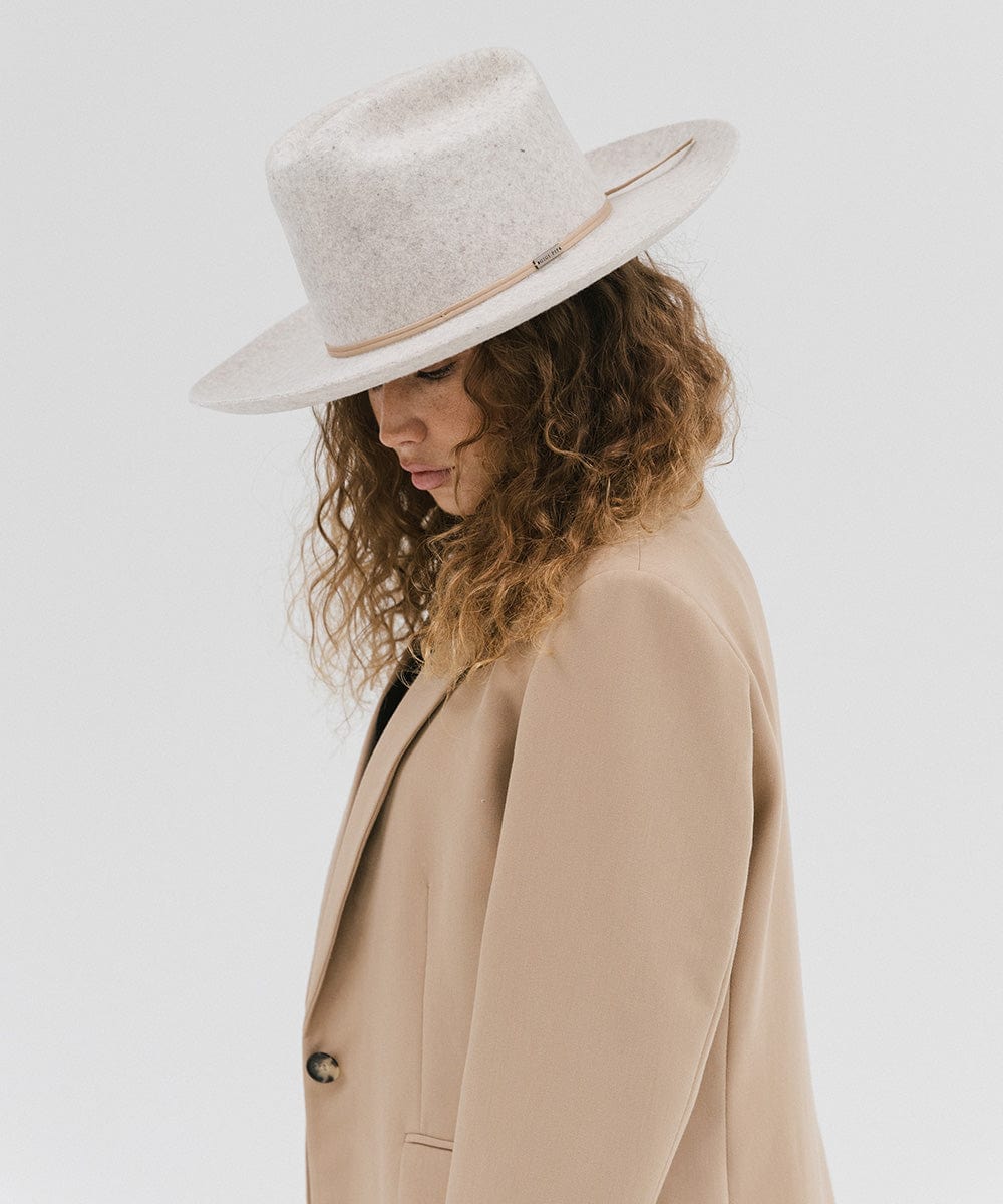 Woman wearing a mix grey colored Western hat with a classic cattleman crown and a hat band, and a beige coat against a plain background  #color_mix grey