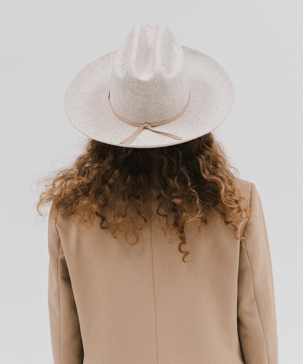 Person wearing a mix grey colored Western hat with a classic cattleman crown and a hat band, and a beige coat, facing behind against a plain background  #color_mix grey