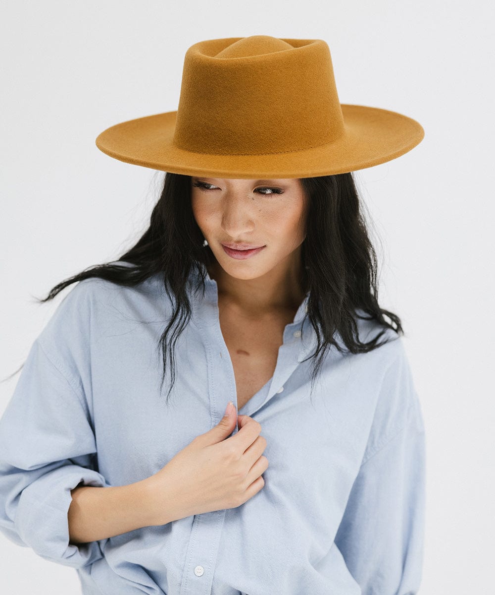 Woman wearing a cinnamon colored gambler hat and a blue shirt against a plain background #color_cinnamon