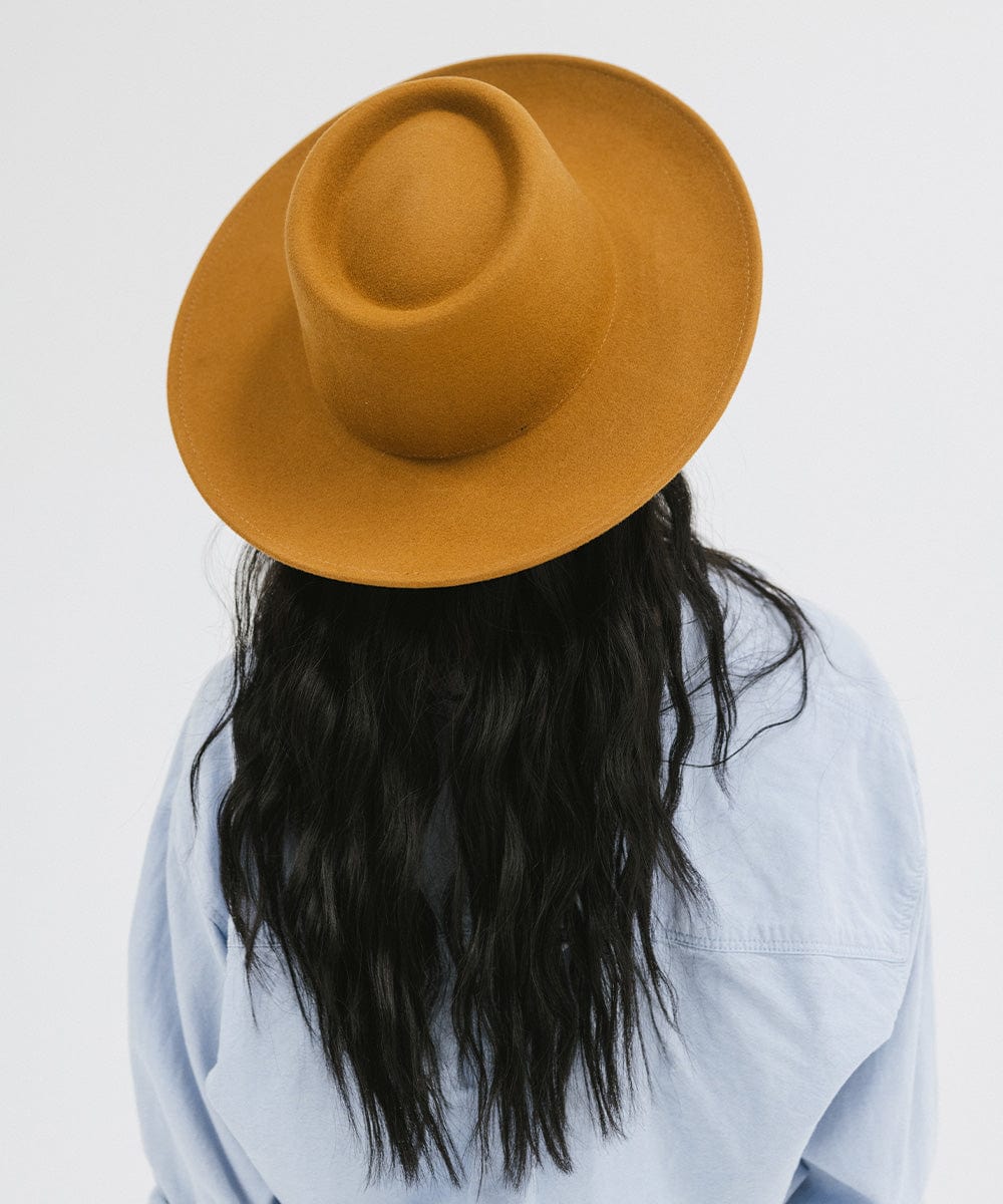 Person wearing a cinnamon colored gambler hat and a blue shirt against a plain background #color_cinnamon