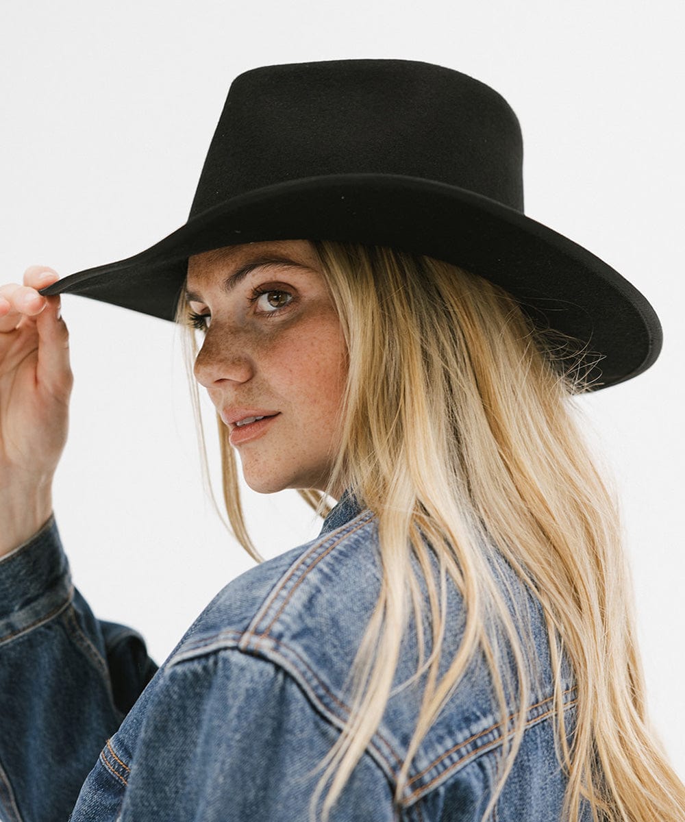 Woman wearing a black felt western hat and a denim shirt, posing against a white background #color_black